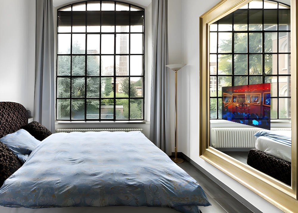 King-size bedroom within a luxurious hotel with a wide, unique mirror TV and a glass window.