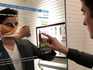 Man is pointing at a screen to order leather shoes on a smart-touch mirror TV in Oman.