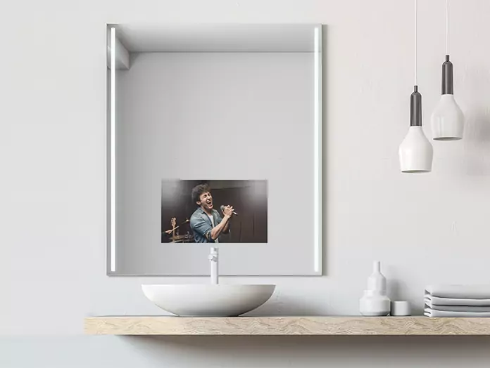 Mirror TV with cool light on either side over a white washbowl on a wooden bar top, in Ajman.
